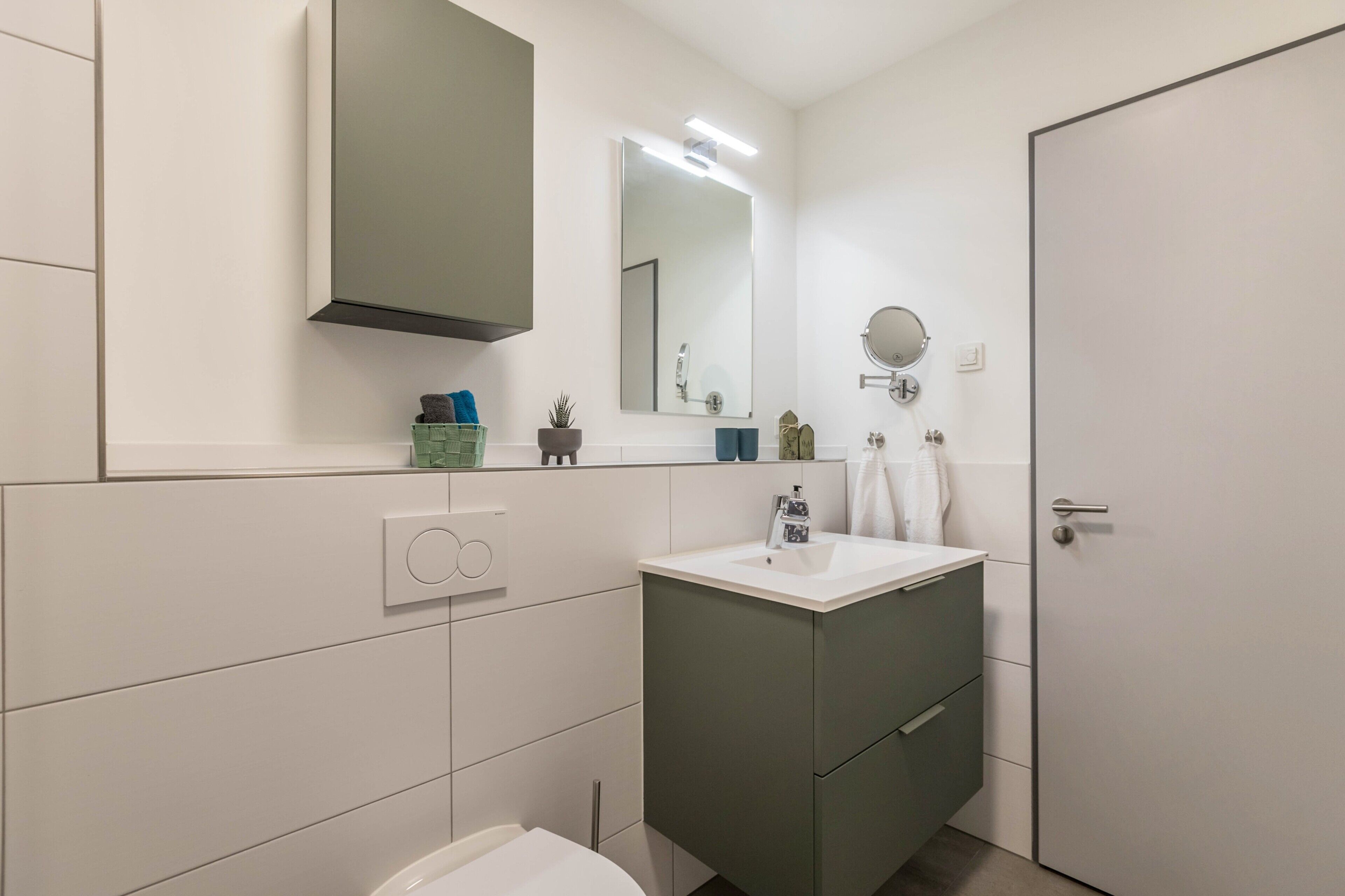 A modern bathroom with a toilet, sink, and mirror.