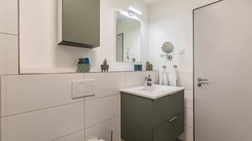 A modern bathroom with a toilet, sink, and mirror.