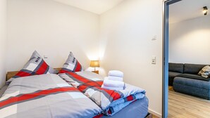A bedroom with a bed, pillows, a lamp, and a view of a living area. - Apartment 'Winderatt 2' with Private Terrace, Shared Garden and Wi-Fi (Husby)