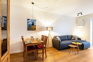 Une pièce comprenant une table à manger, des chaises, un canapé, un lampadaire et un tableau accroché au mur.