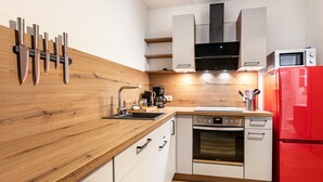 A modern kitchen with wooden countertops, white cabinets, a red refrigerator, and a built-in oven. - Apartment 'Winderatt 2' with Private Terrace, Shared Garden and Wi-Fi (Husby)