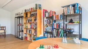 A room with a wooden table, a chessboard, and two bookshelves filled with books. - Apartment 'Winderatt 2' with Private Terrace, Shared Garden and Wi-Fi (Husby)