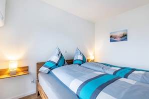 Un lit double avec une literie à rayures, des lampes de chevet, une tête de lit en bois et un tableau accroché au mur.