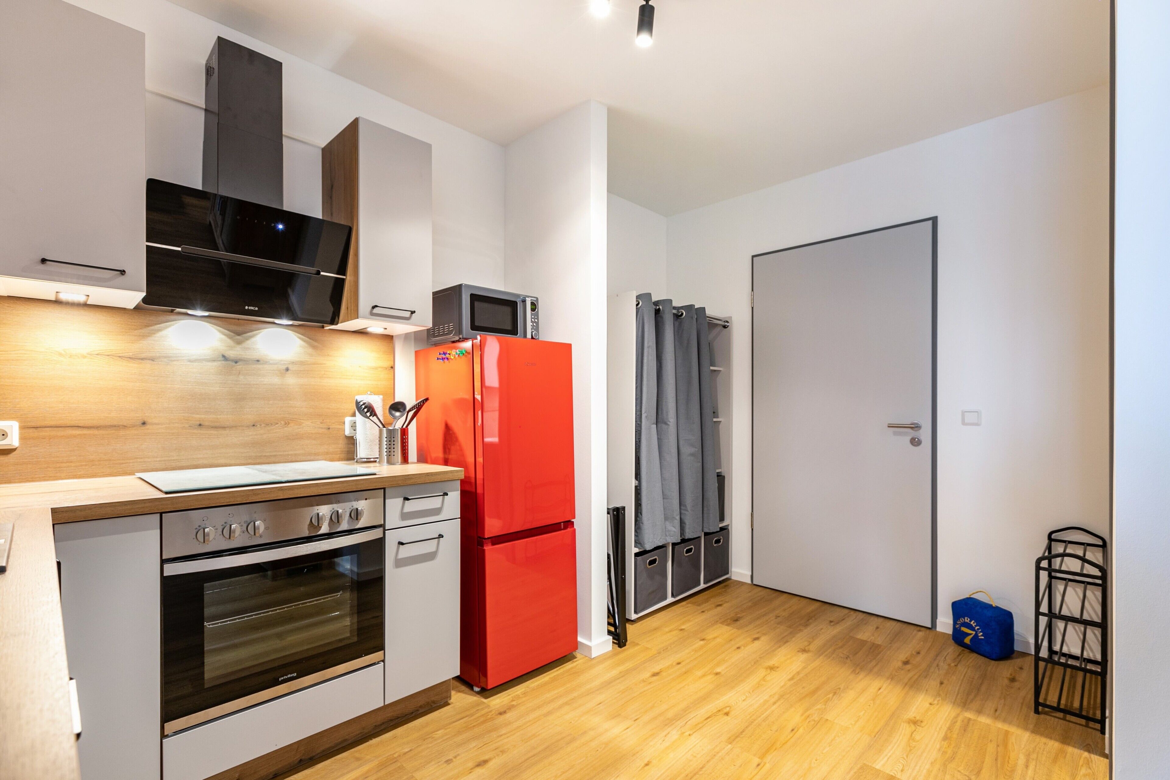 Eine moderne Küche mit Backofen, Mikrowelle und einem roten Kühlschrank.