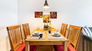 Ruokapöytä tuoleineen, riippuvalaisin ja taideteos seinällä.