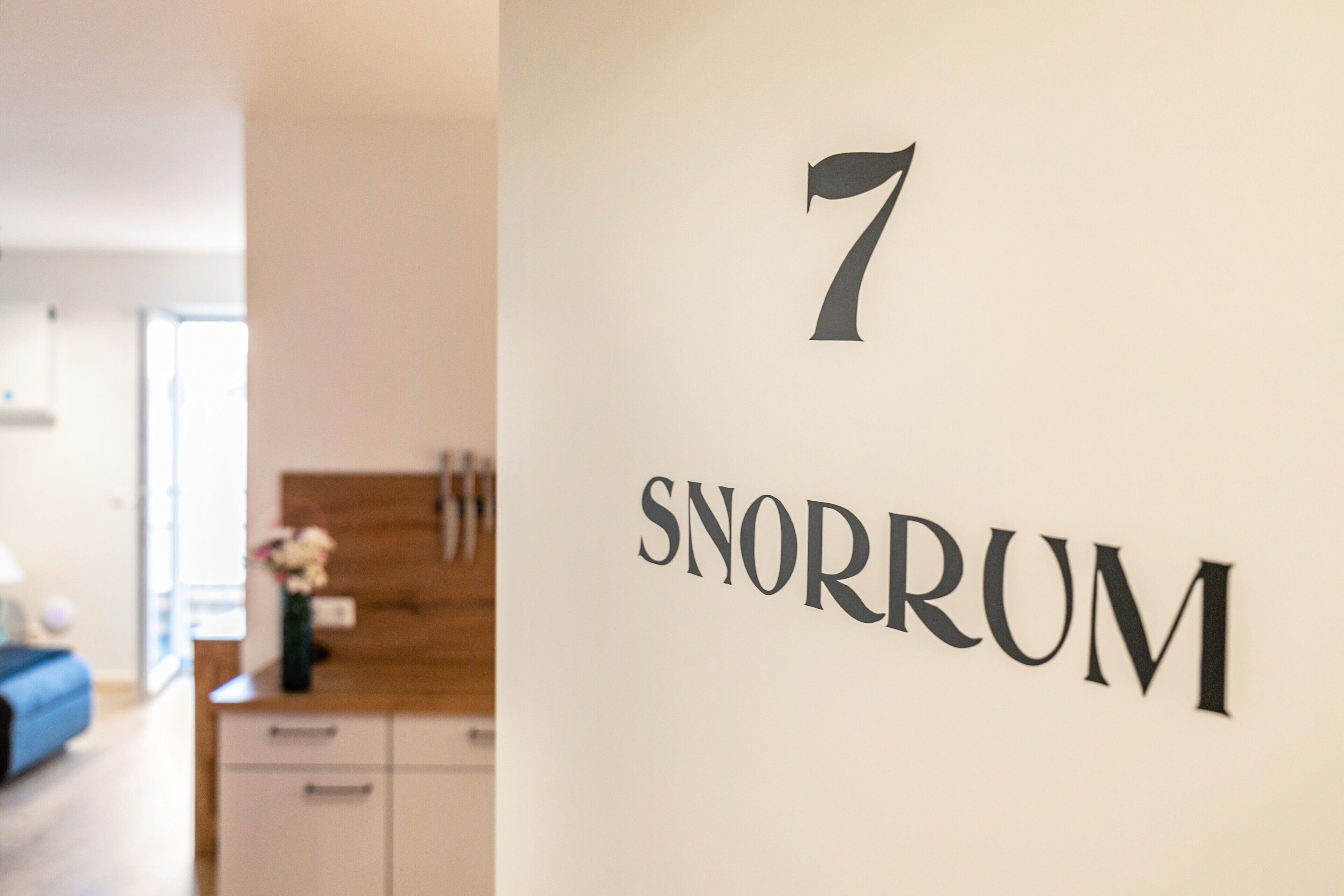 Un muro con il numero '7' e la scritta 'SNORRUM', numero di una camera d'albergo.