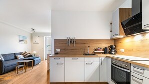 Moderni keittiö, jossa on valkoiset kaapit, puinen työtaso ja sisäänrakennettu uuni.