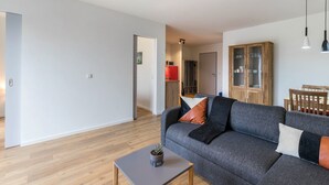 Una sala de estar moderna con un sofá gris, una mesita con una planta y un armario de madera.