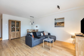 A modern living room with a grey sofa, wooden cabinet, and a small table.