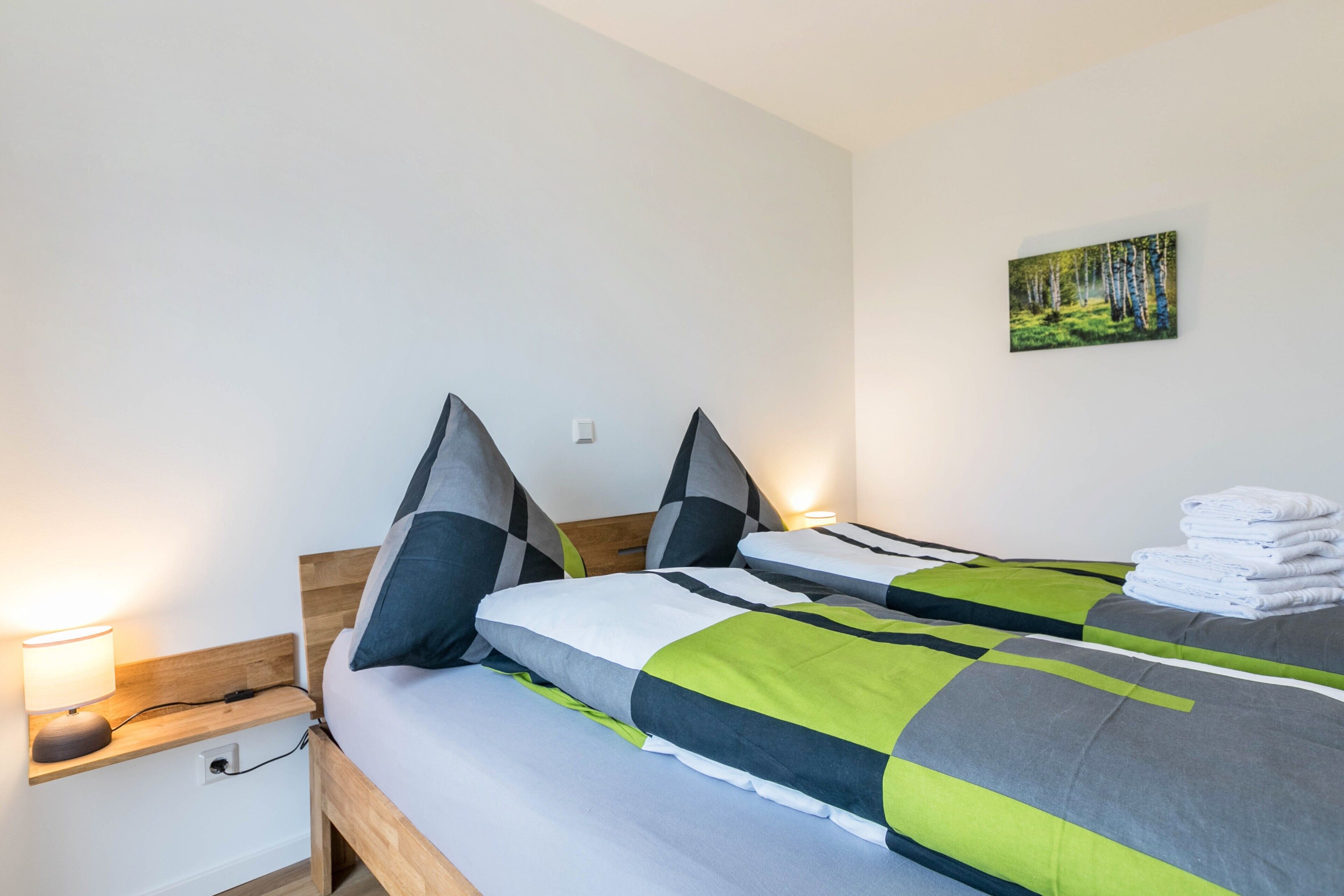 Ein Hotelzimmer mit zwei Betten, einem Nachttisch mit Lampe und einem Bild an der Wand.