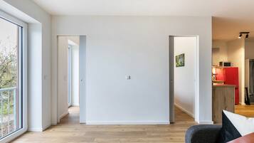 Un interior moderno con piso de madera, un sofá gris y una zona de cocina roja.