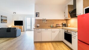 Una cocina moderna con armarios de madera, un refrigerador rojo y un horno empotrado.