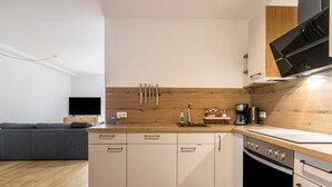 Una cocina moderna con armarios de madera, horno integrado y televisor de pantalla plana.