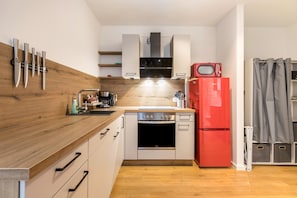 Une cuisine compacte dotée d’un plan de travail en bois, d’un lave-vaisselle, d’un réfrigérateur rouge et d’un four à micro-ondes.