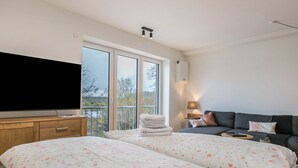 Un dormitorio con cama, televisor, sofá y balcón con vistas.