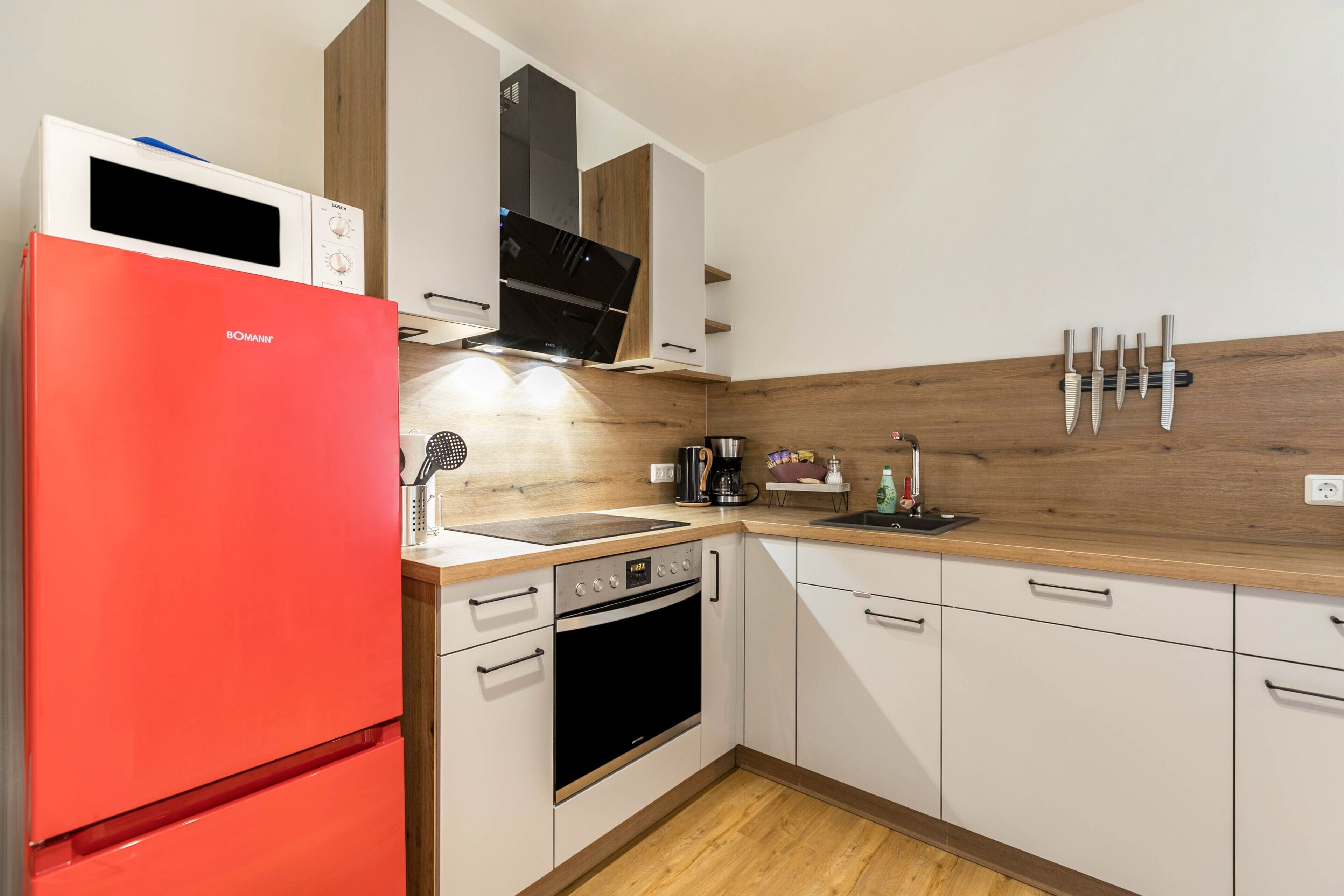 A kitchen with a red refrigerator, a microwave, a stove, and a coffee maker.