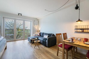 Un salon moderne avec un canapé, une table à manger, des chaises et de grandes fenêtres.
