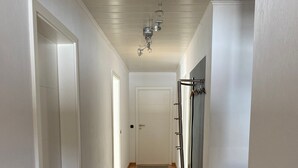 Ein Flur mit Holzdielen, einem grauen Teppich, weißen Wänden und einem Deckenventilator.
