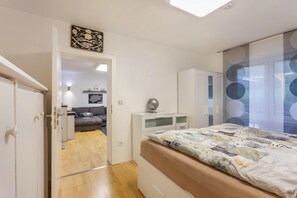 A bedroom with a bed, a wardrobe, a desk, and a window with circular blinds. - Apartment 'Zur Quelle' with Private Terrace, Private Garden and Wi-Fi (Plettenberg)