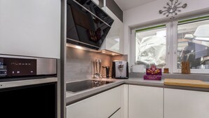 Una cocina moderna con horno integrado, cafetera y ventana con vista a coches estacionados.