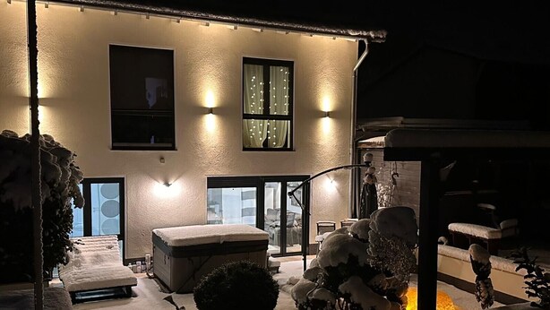Un edificio con un patio cubierto de nieve, una banca y una pequeña mesa.
