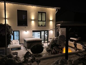 Un bâtiment doté d’un patio enneigé, d’un banc et d’une petite table.