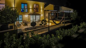 Una casa moderna con un patio, mobiliario exterior y una hamaca.