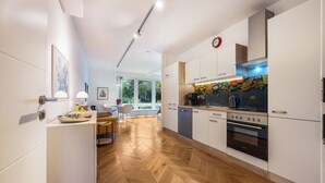 Una cocina moderna con armarios blancos, suelo de madera en espiga y vistas al exterior.