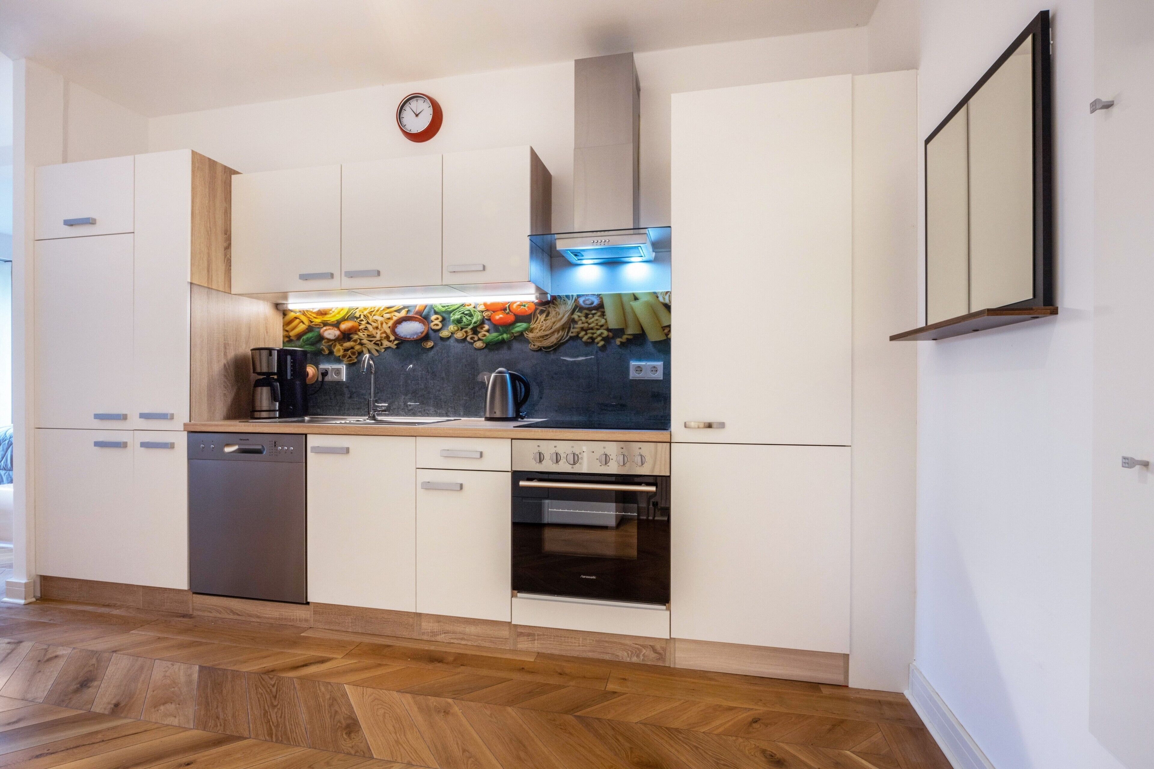 Een moderne keuken met witte kastjes, een vaatwasser, een oven en een magnetron.