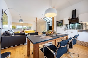 Eine moderne Küche mit Backofen und einer Essecke, inklusive Holztisch und blauen Stühlen.