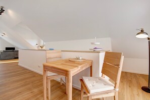Quarto moderno estilo loft com mesa de jantar de madeira, um banco acolchoado e uma pequena ilha com luminária.