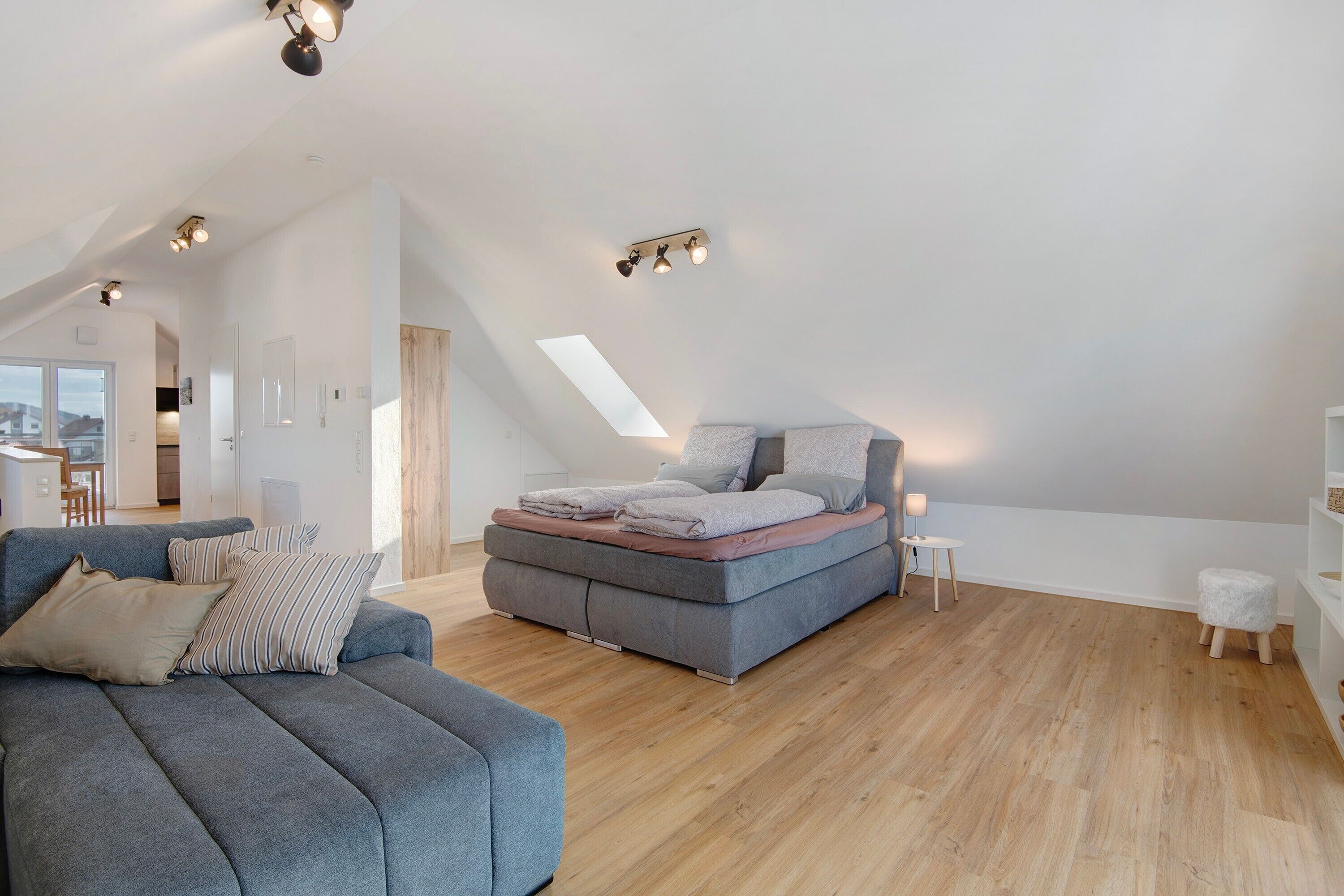 Una habitación amplia con una cama alta, un sofá y una pequeña mesa.