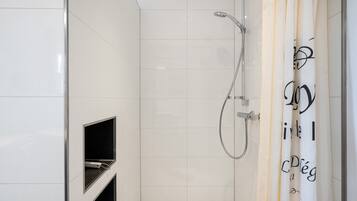 Ein modernes Badezimmer mit weißen Fliesen, einer Dusche inklusive Handbrause und einem Handtuchhalter mit einem Handtuch.