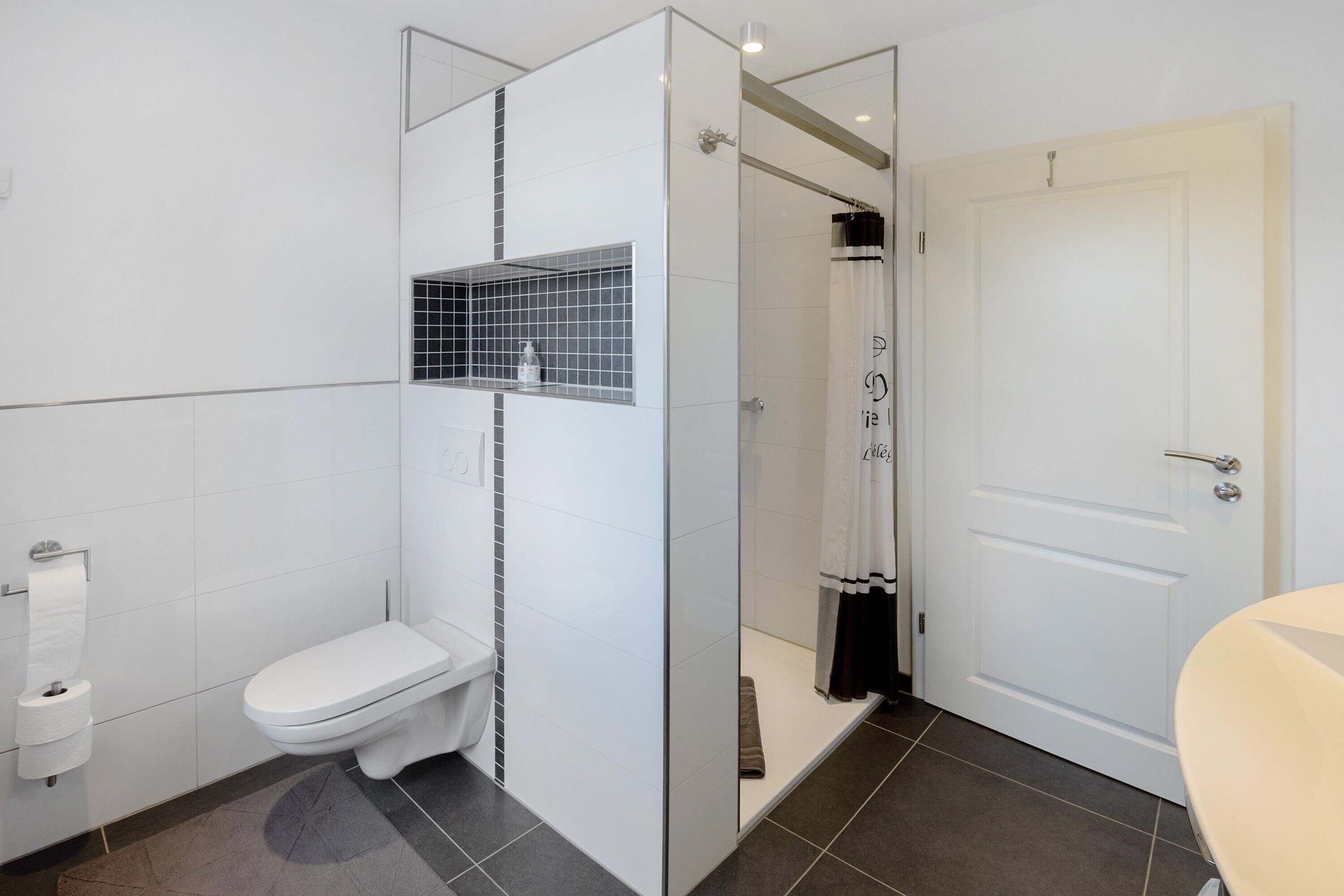 Ein modernes Badezimmer mit Toilette, Duschkabine und Tür.