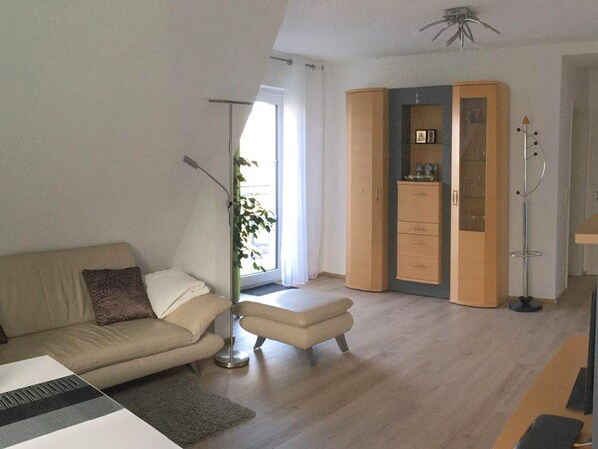 A modern living room with a sofa, ottoman, floor lamp, and a wardrobe with a mirror.