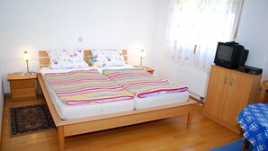 Un dormitori amb un llit de fusta, dues taules de nit, una televisió i un armari.