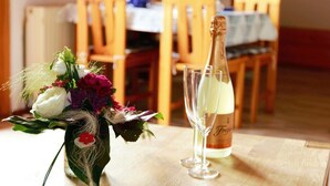 A dining table with a bottle of champagne, a glass, and a floral arrangement. - Apartment 'Ferienwohnung 3, 70 Qm' with Shared Garden, Balcony and Wi-Fi (Owingen)
