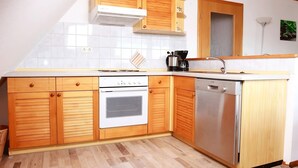 A kitchen with wooden cabinets, a white stove, and a dishwasher. - Apartment 'Ferienwohnung 3, 70 Qm' with Shared Garden, Balcony and Wi-Fi (Owingen)