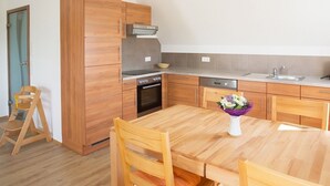 Uma cozinha compacta com armários de madeira, forno embutido, lava-louças e mesa de jantar com cadeiras.