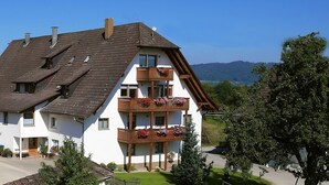 A two-story building with a sloped roof, balconies with flower boxes, and a view of the surrounding landscape. - Holiday Home 'Haus 1, 80 Qm, 2 Schlafzimmer' with Private Terrace, Shared Garden and Wi-Fi (Owingen)
