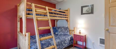 Un lit superposé avec une échelle en bois, une table de chevet avec une lampe et un tableau encadré au mur.