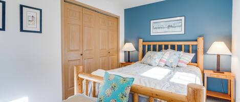 A bedroom with a wooden bed, two bedside tables with lamps, a large wooden door, and a framed picture on the wall.