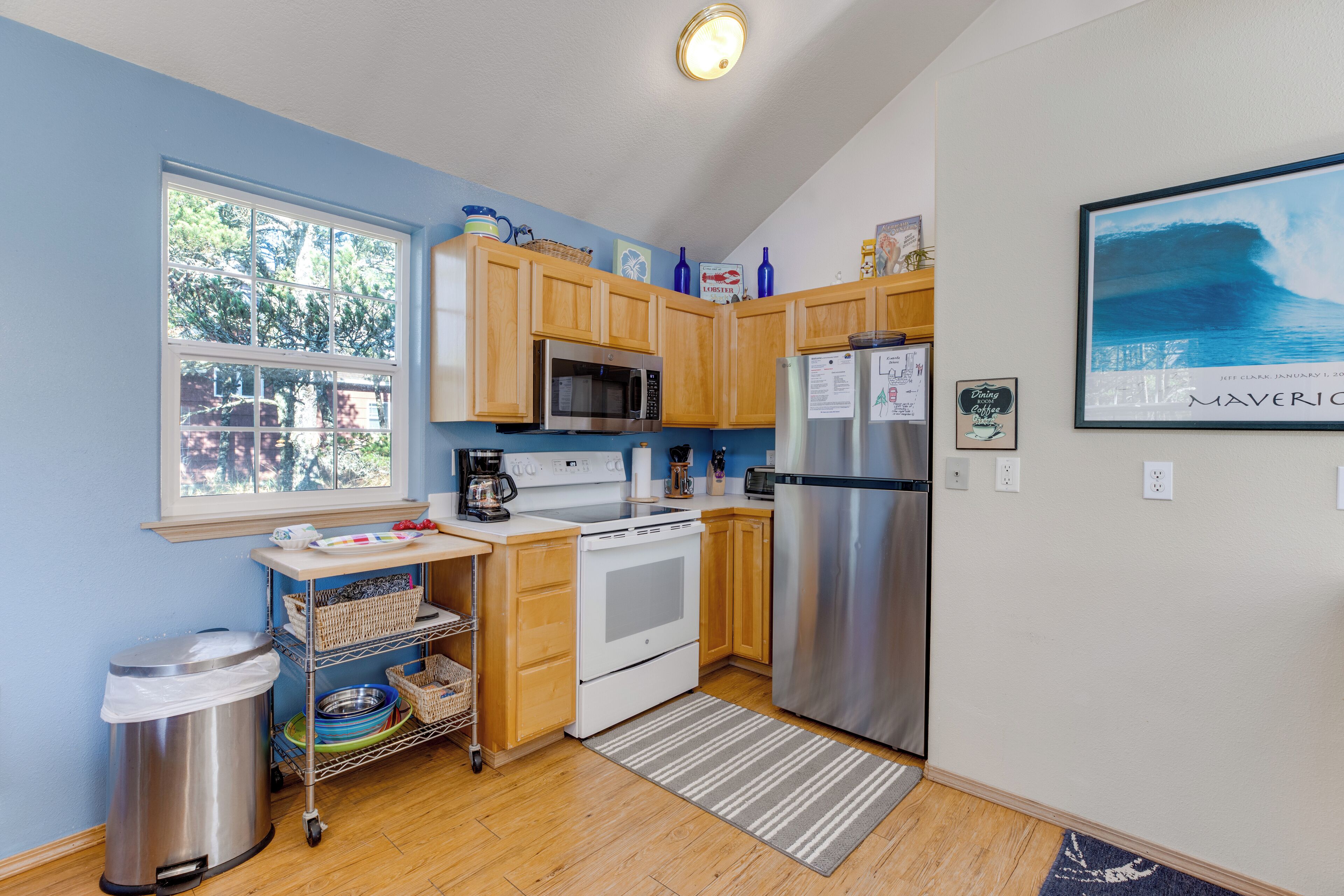 A kitchen with wooden cabinets, stainless steel appliances, a window, and a view of the ocean.