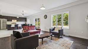 A spacious living area with a modern kitchen, a red leather sofa, a gray armchair, and a coffee table. - Amazing stay near Hamilton-Brantford- Beach Port Dover (Norfolk)