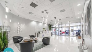 Um lobby moderno com balcão de recepção, área de estar e entrada de vidro para a área de estacionamento.