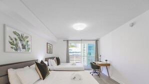 Quarto de hotel com cama, escrivaninha e varanda com vista para a cidade.