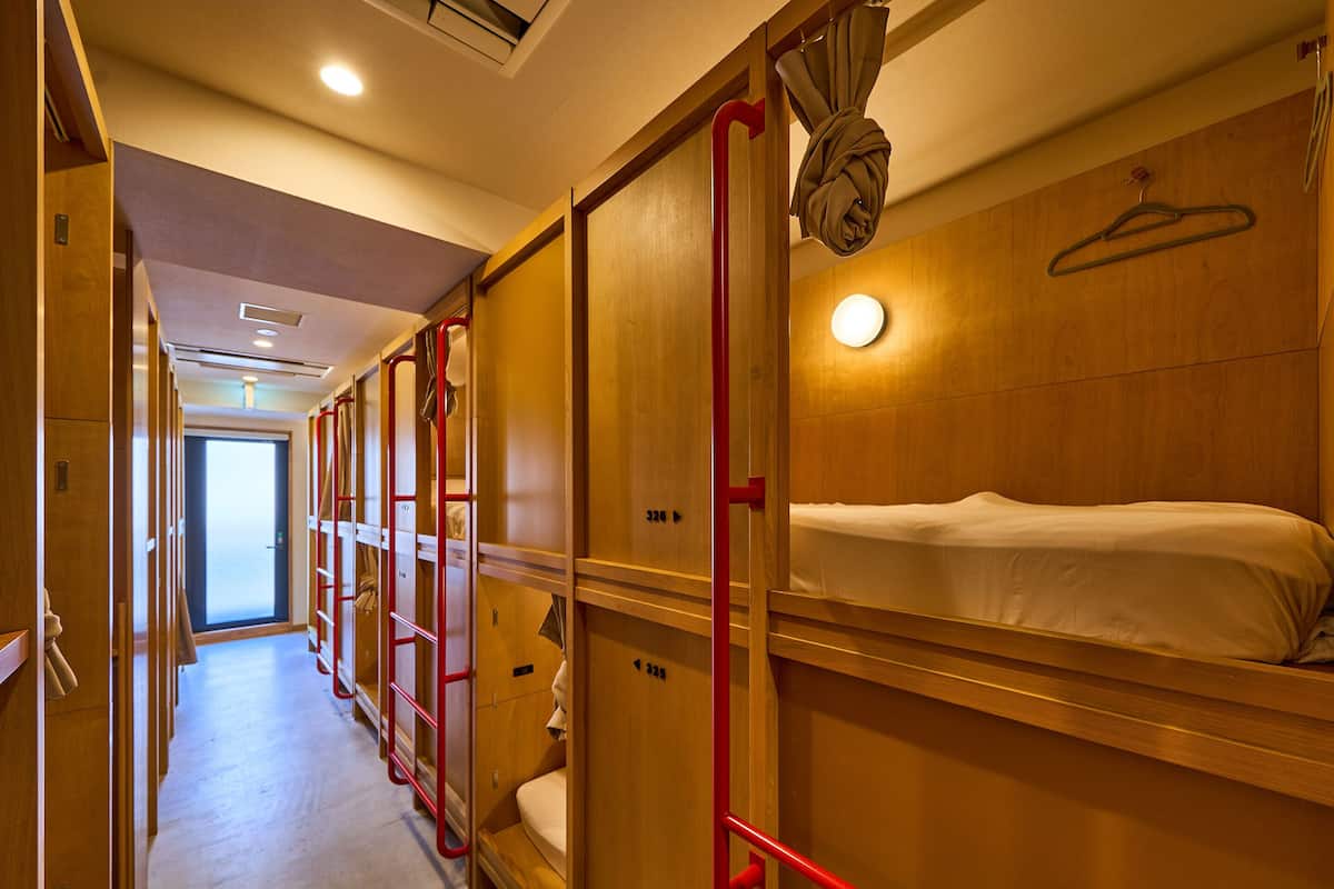 A hotel corridor with wooden bunk beds, red handrails, and a hanging towel.