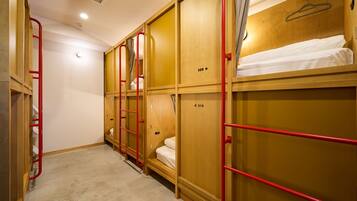 A dormitory room with bunk beds, numbered doors, and a red ladder.
