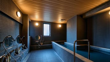 Una sauna pública con varias bancas y una zona central de hidromasaje.