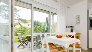 A modern kitchen with white cabinets, a microwave, and a dining area with a table and chairs. - Apartment Nixe by Interhome (Koserow)